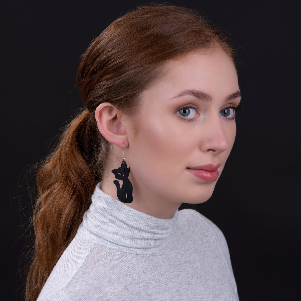Woman wearing Paguro Upcycle recycled rubber cat earrings in black with silver hooks