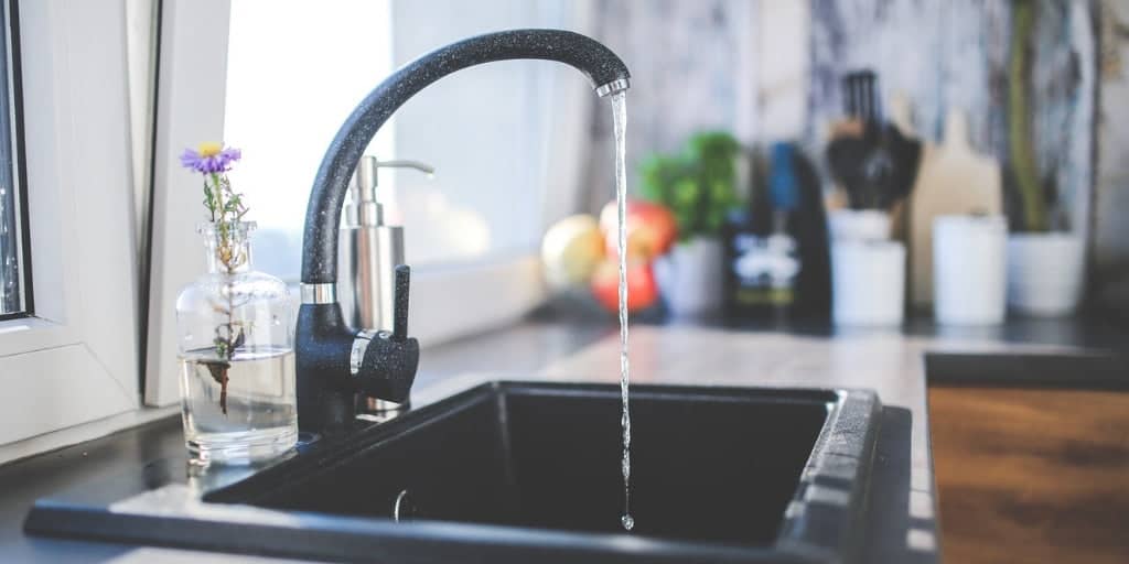 Modern kitchen sink with flowing water and decorative items, illustrating how to upcycle household items