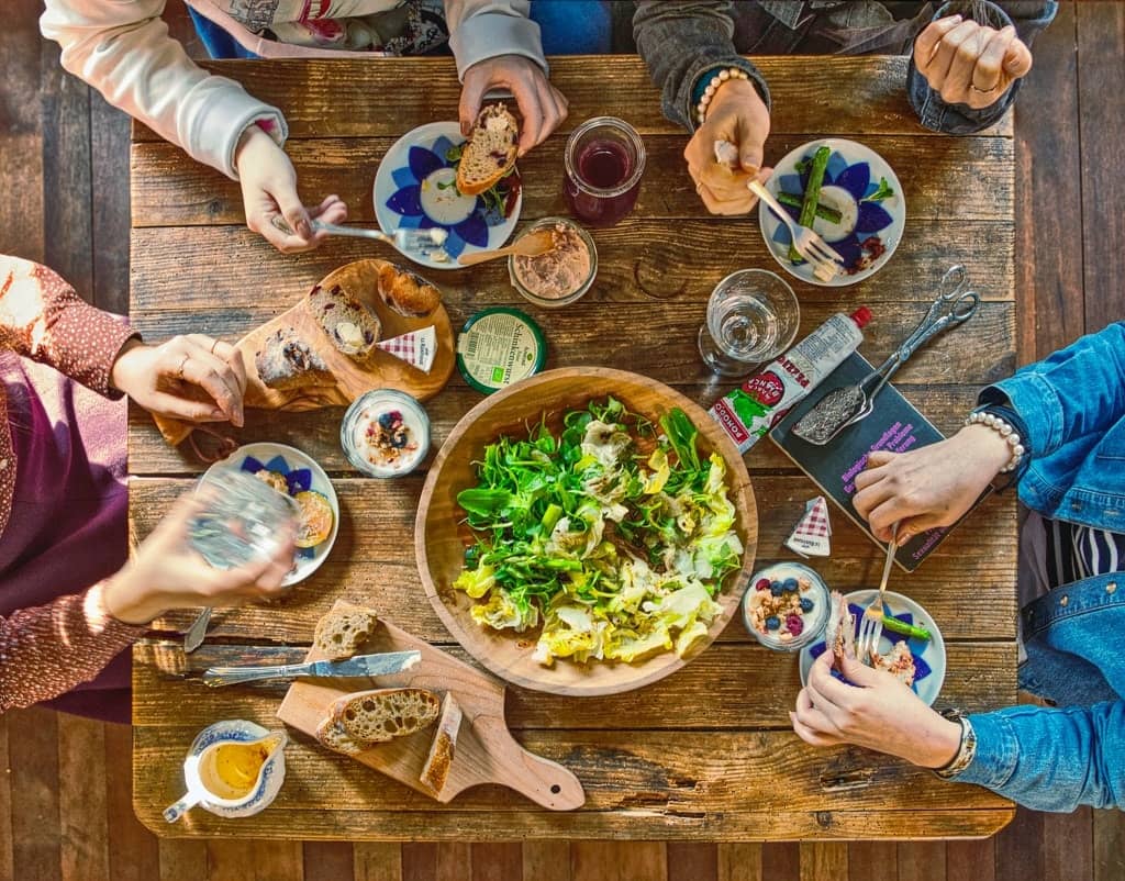 A group enjoying a communal meal featuring fresh salad and vegan dishes for the complete guide to going vegan