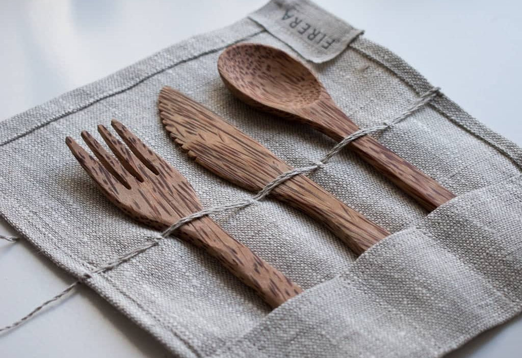 Eco-friendly bamboo utensils arranged in a linen pouch for a sustainable living guide