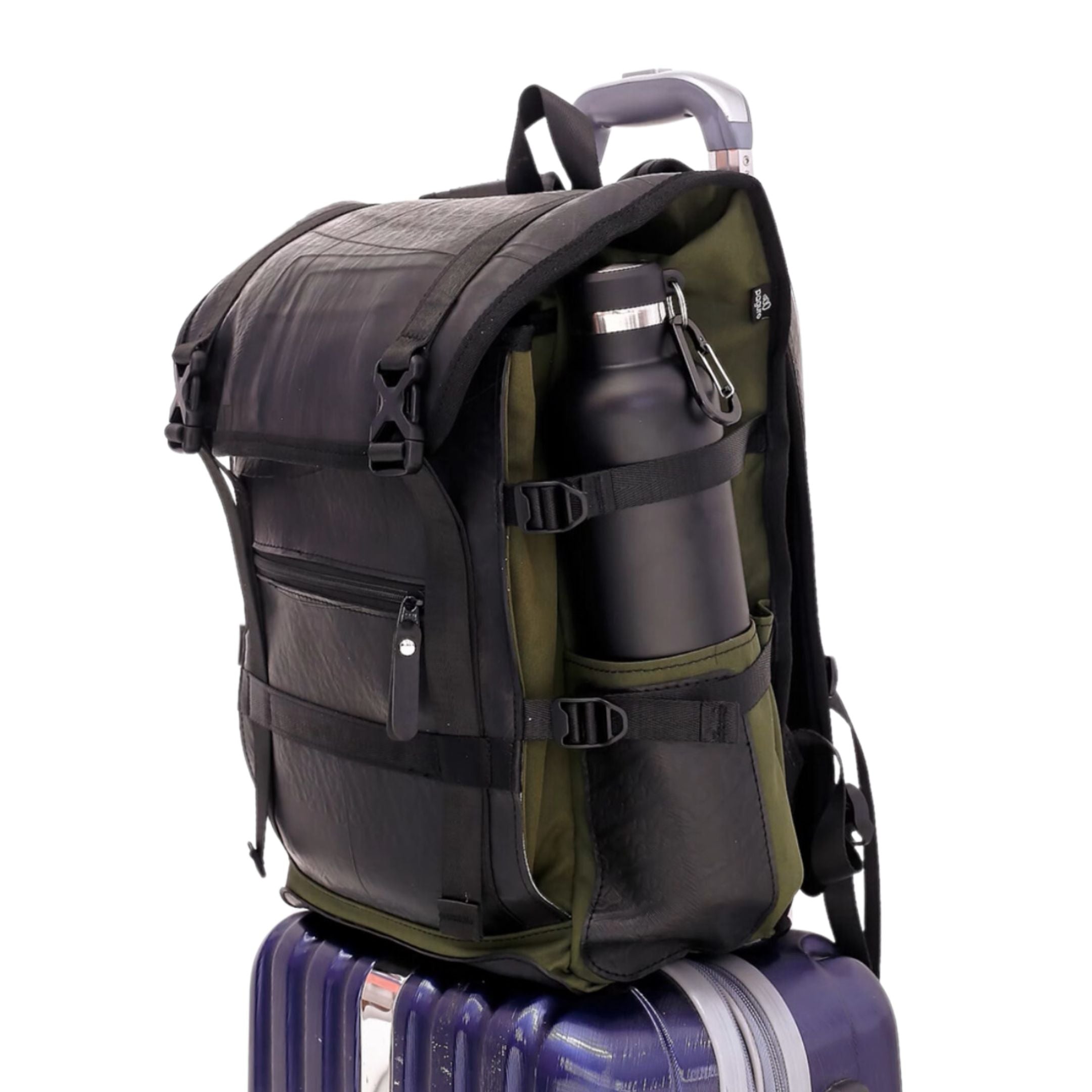 A black and green backpack with a water bottle on top of a blue suitcase.