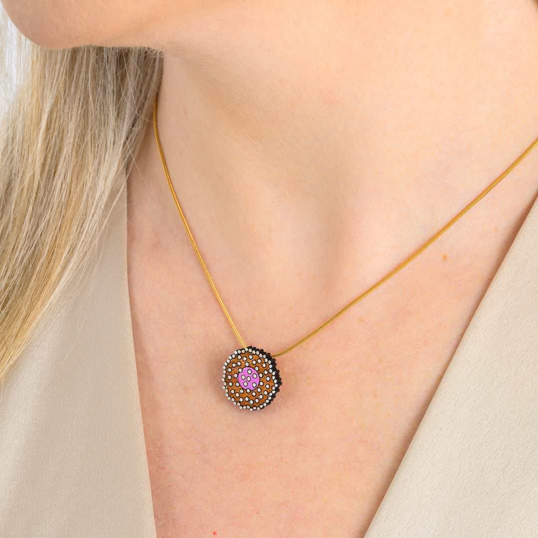Paguro Upcycle reclaimed wood necklace with circular painted design worn on a gold chain