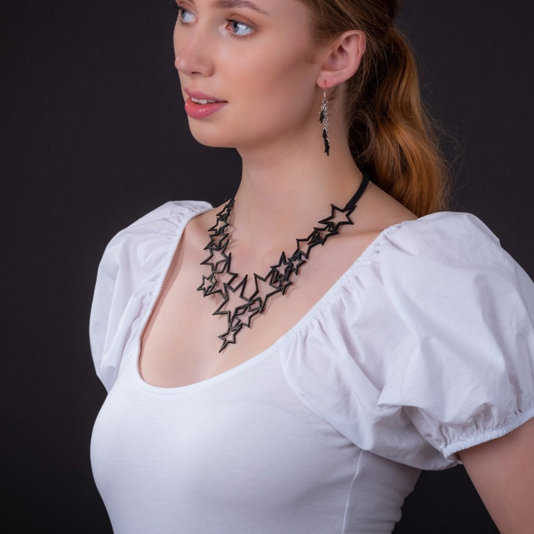 Model wearing the Star Set: black recycled inner tube Star necklace and matching earrings by Paguro Upcycle