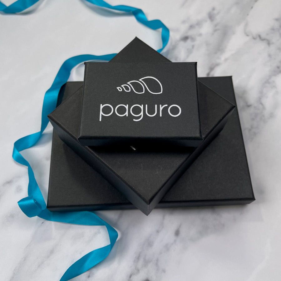 Paguro Upcycle black jewelry boxes stacked with blue ribbon on marble surface for reclaimed wood necklace