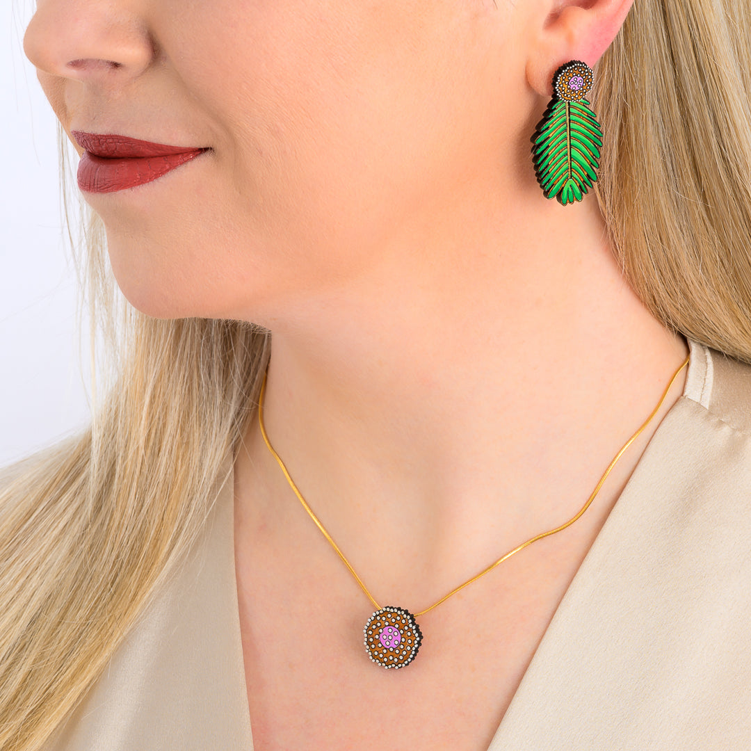 Paguro Upcycle reclaimed wood earrings shaped like green leaves worn on a woman with matching reclaimed wood necklace