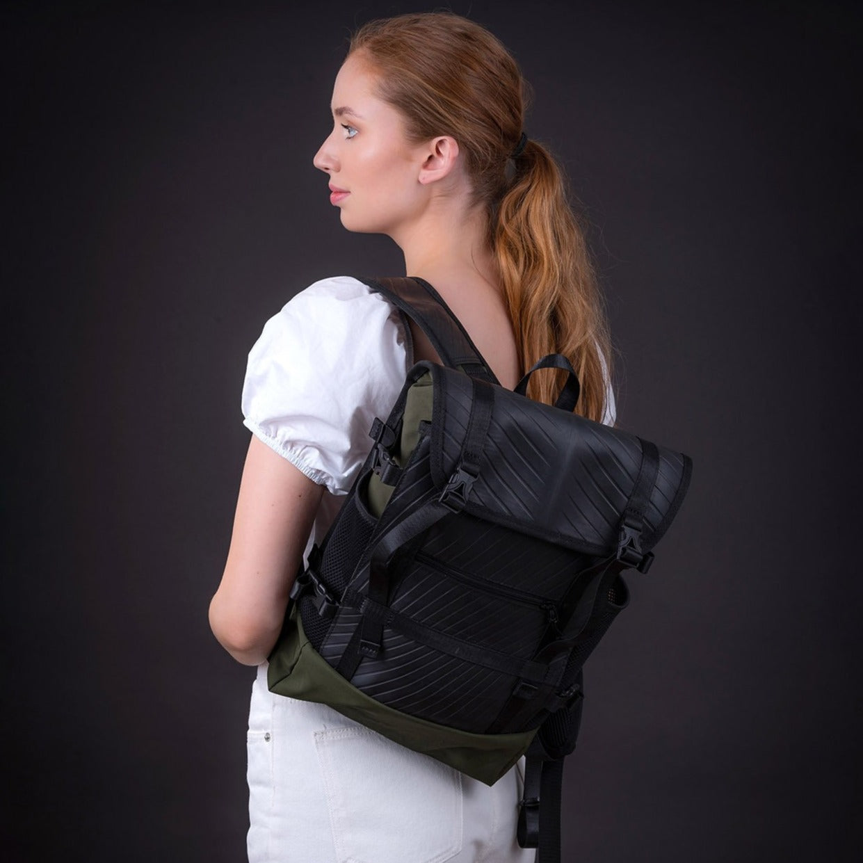 Person wearing a black and green backpack with a dark background.