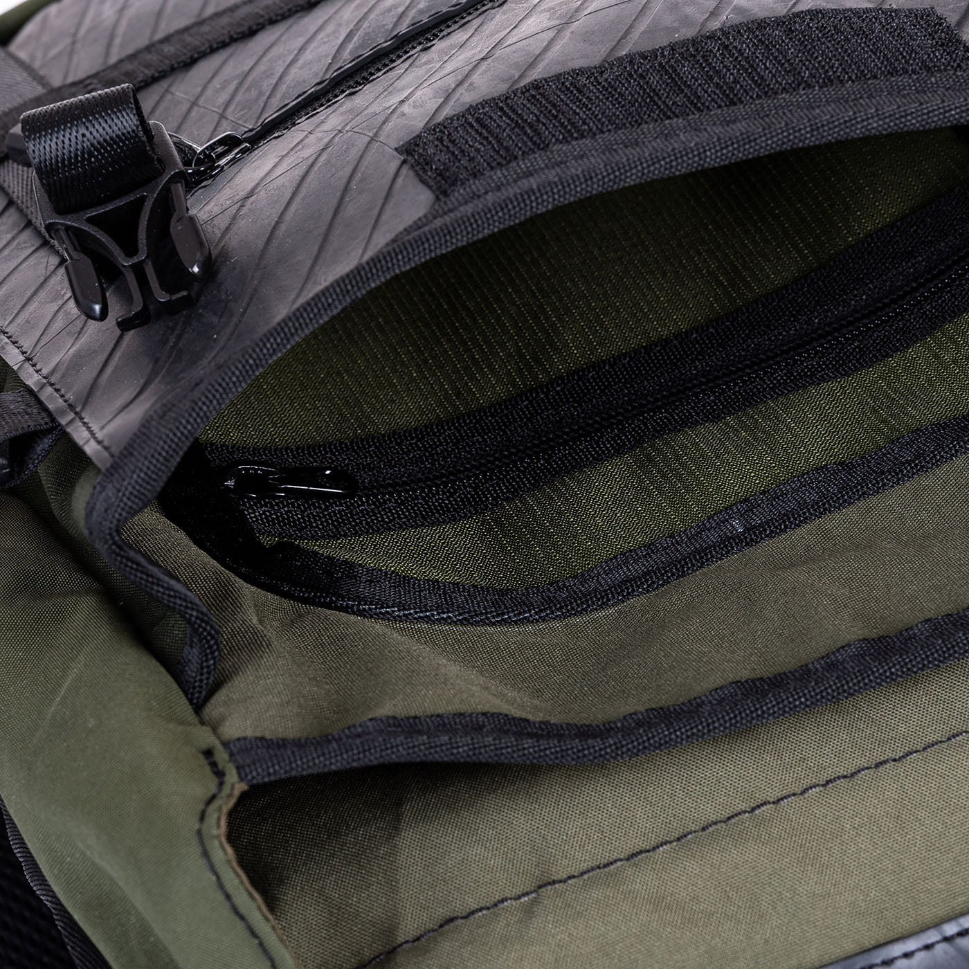 Open green and black backpack showing multiple compartments.