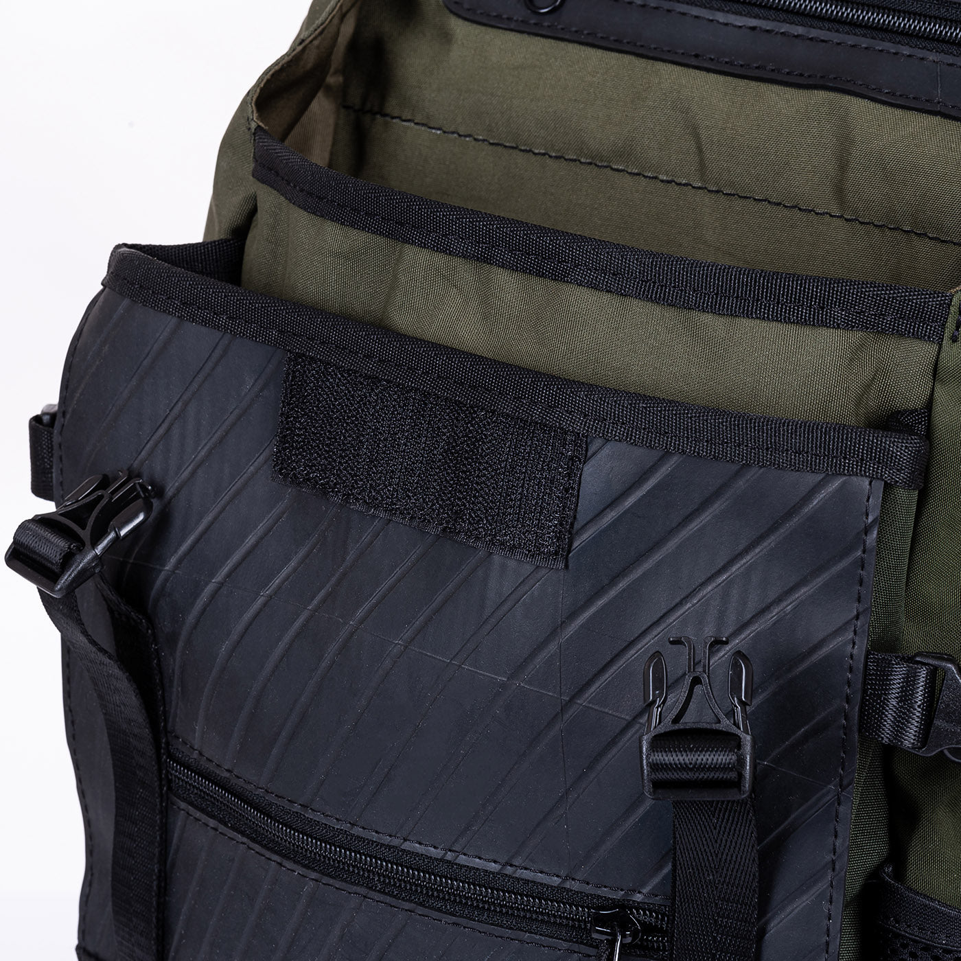Close-up of a black and olive green backpack with multiple pockets and buckles.