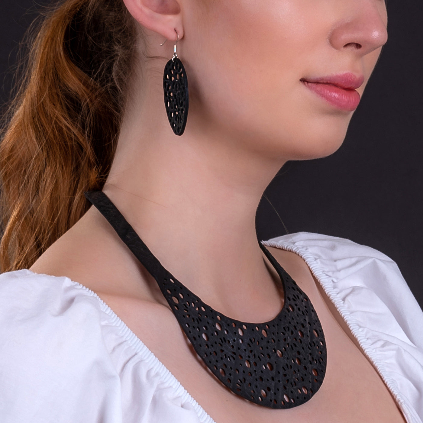 Paguro Upcycle recycled rubber earrings UK black perforated teardrop earrings on model showing sustainable jewellery
