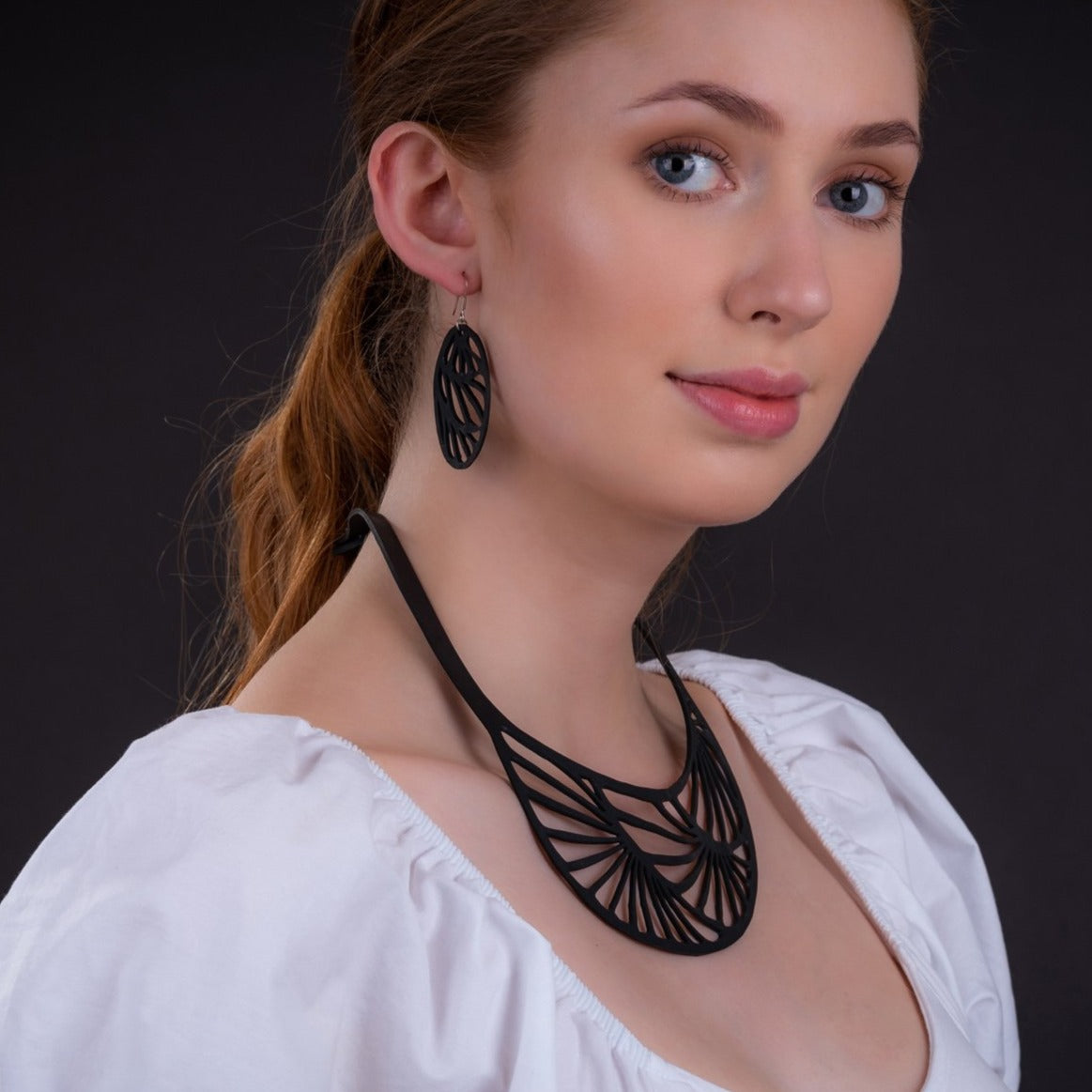 Paguro Upcycle black recycled rubber earrings with geometric cutout design worn by model with matching necklace