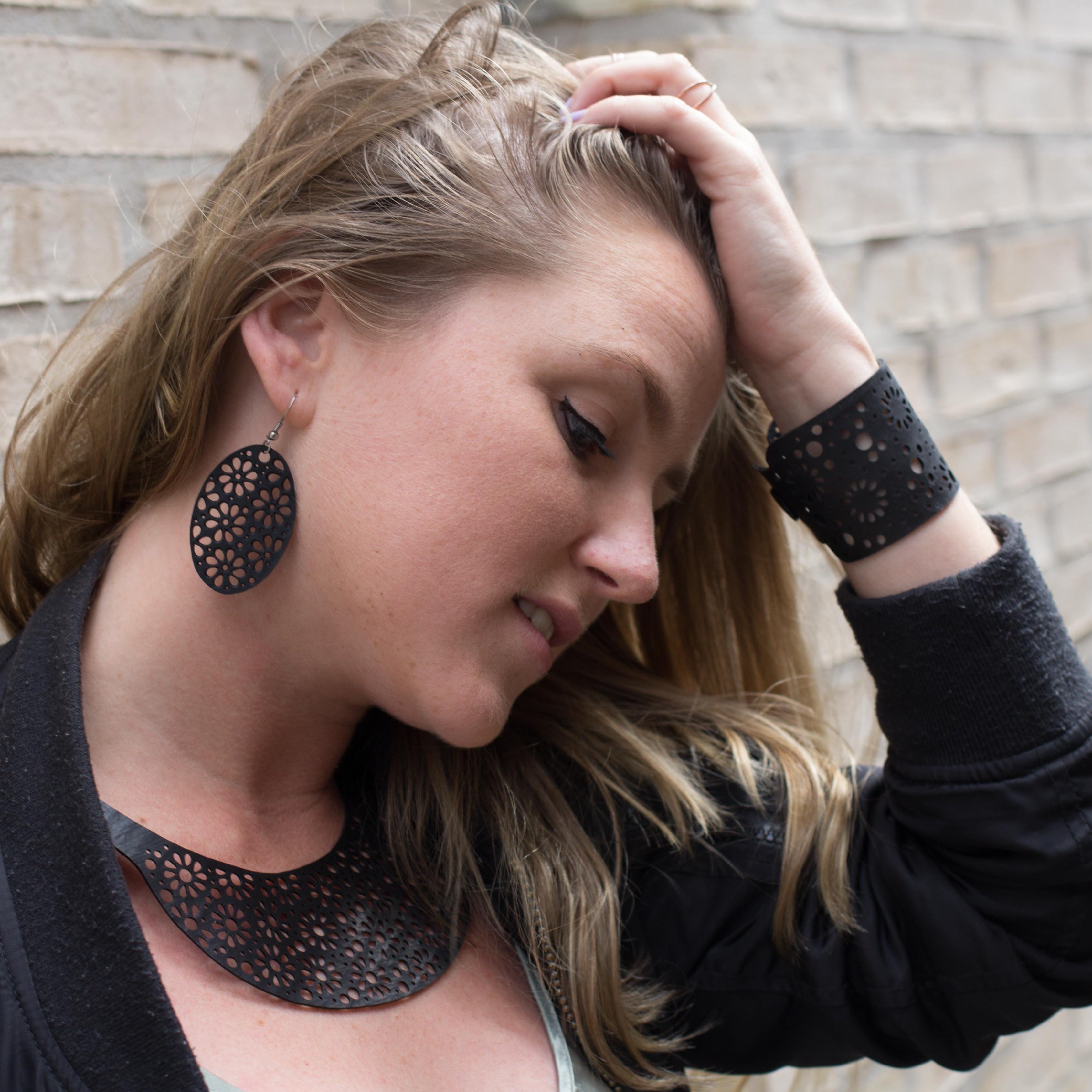 Paguro Upcycle upcycled inner tube necklace worn by woman with matching black cutout cuff and earrings