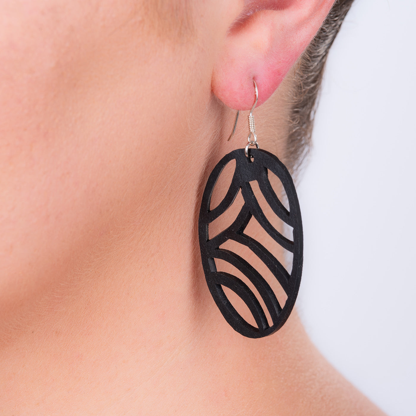 Paguro Upcycle recycled rubber earrings black oval cutout dangle with silver hook shown on ear