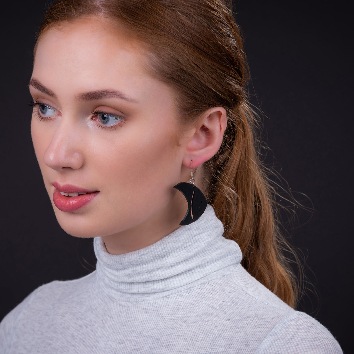 Paguro Upcycle black crescent moon recycled rubber earrings worn by woman in grey turtleneck
