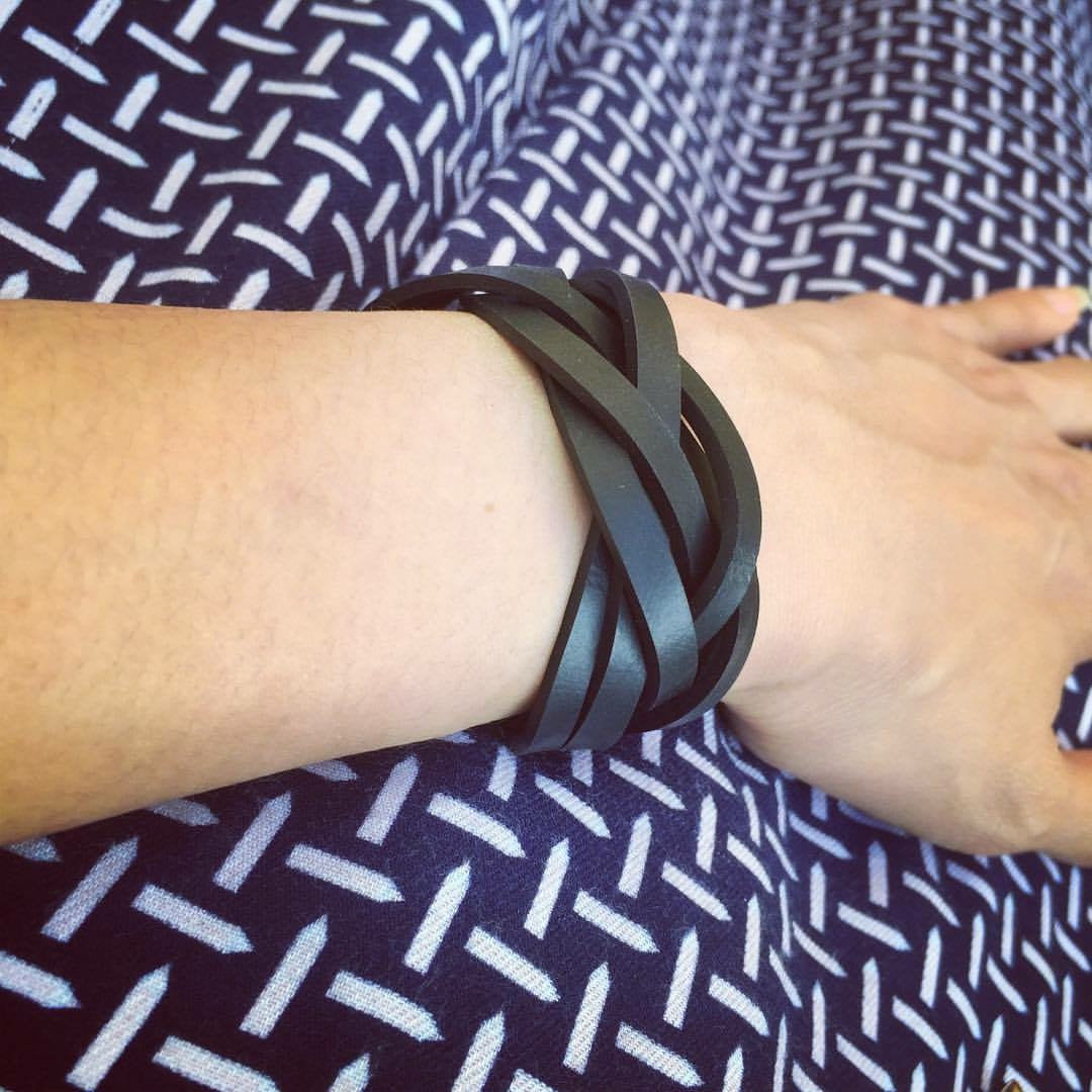 Paguro Upcycle recycled rubber bracelet UK black braided multi strand cuff on wrist over patterned fabric
