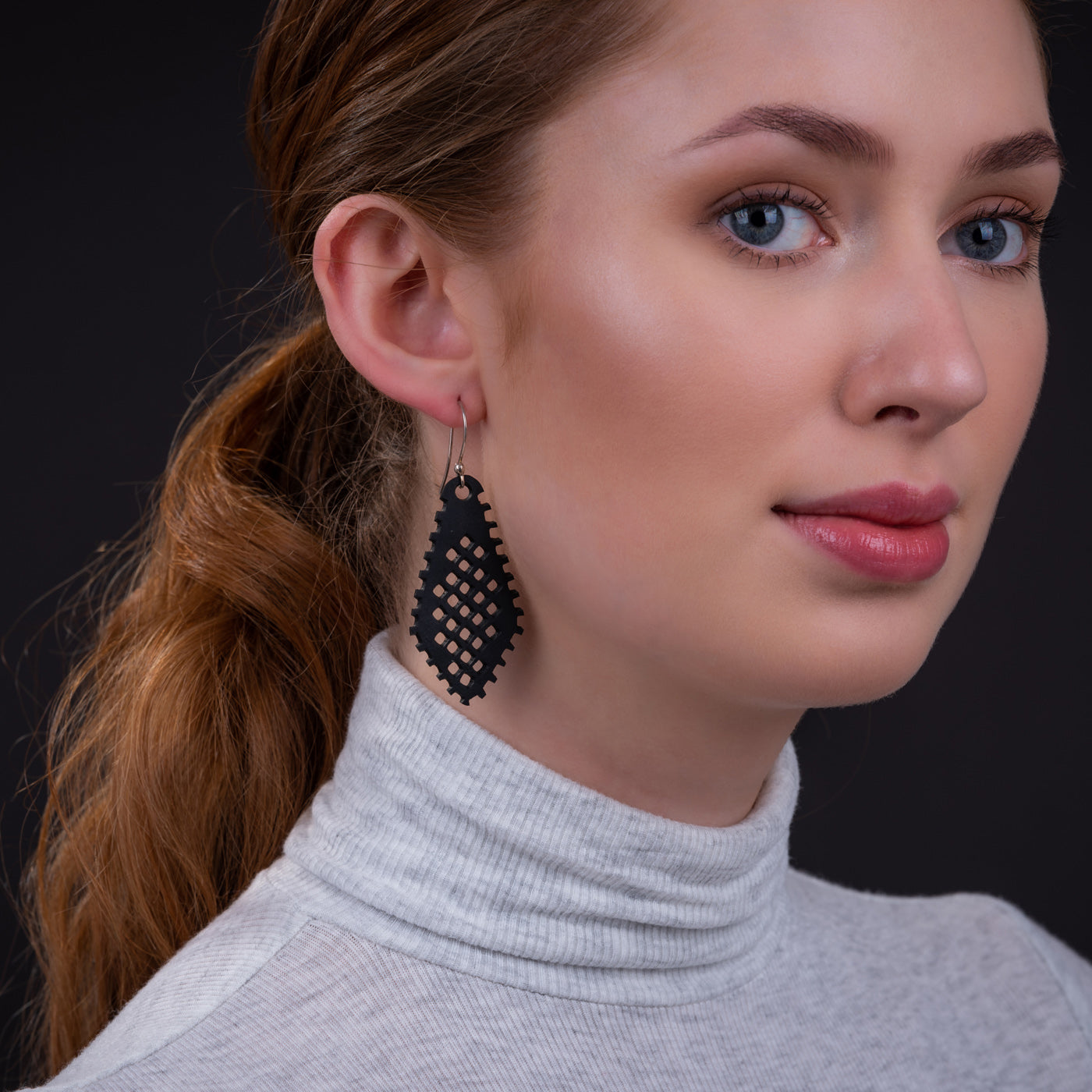 Woman wearing black recycled rubber earrings with geometric cutout design by Paguro Upcycle