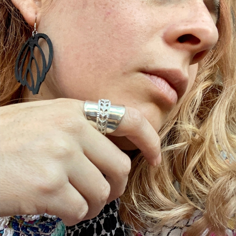 Paguro Upcycle black layered leaf recycled rubber earrings UK on model with silver ring and curly hair