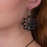 Paguro Upcycle recycled rubber flower earrings worn on ear with black floral design