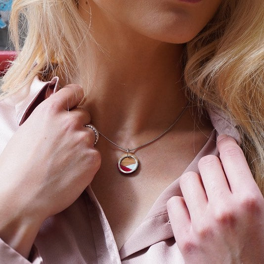 Woman wearing a recycled wood silver necklace with a circular pendant from Paguro Upcycle