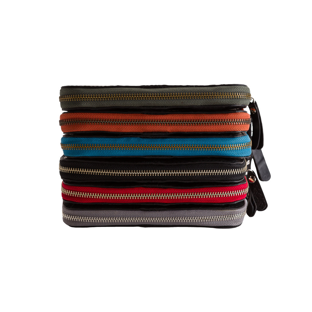 Stack of colorful vegan long zip purse wallets by Paguro Upcycle with visible metal zippers