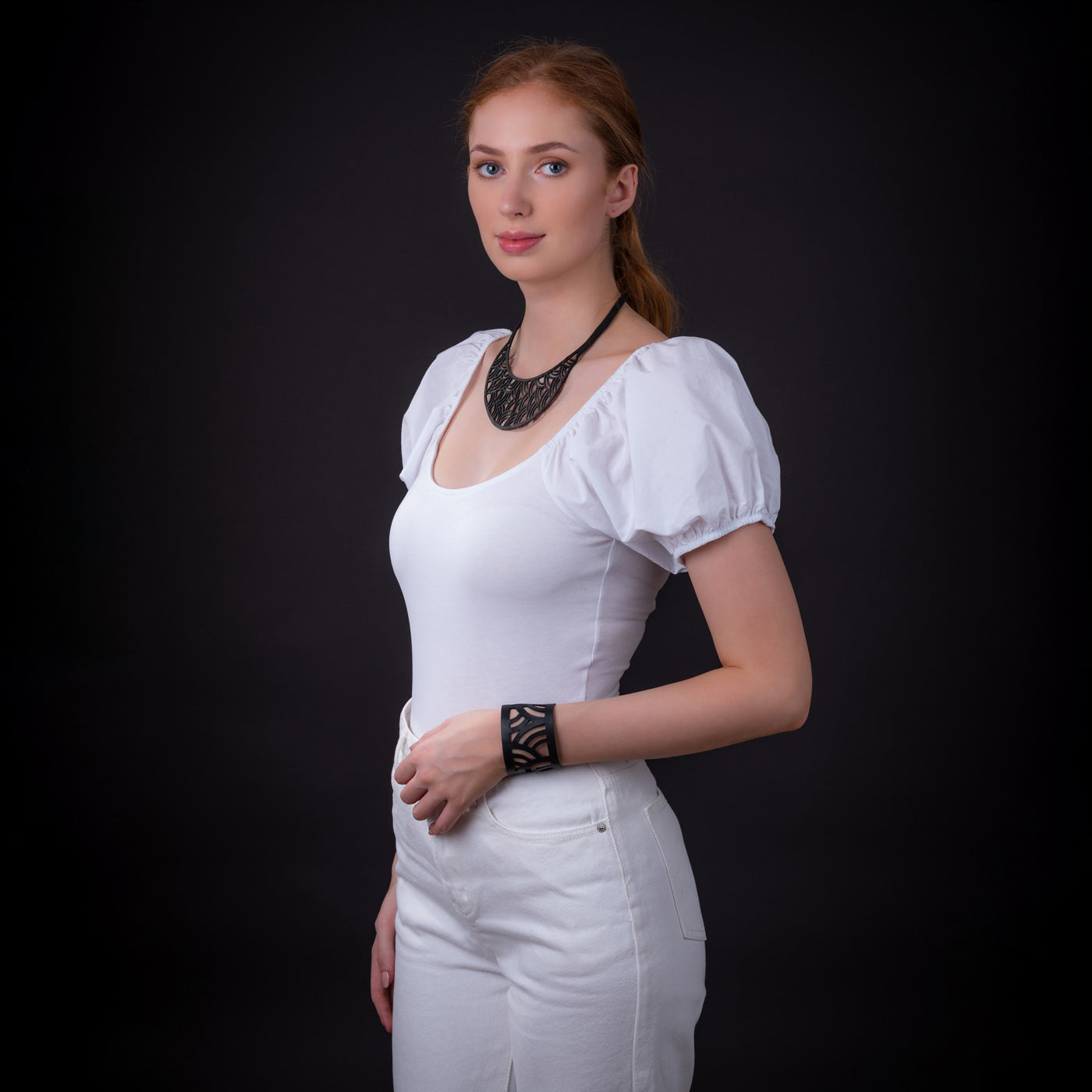 Paguro Upcycle model wearing black upcycled inner tube necklace and matching cuff with white puff sleeve top