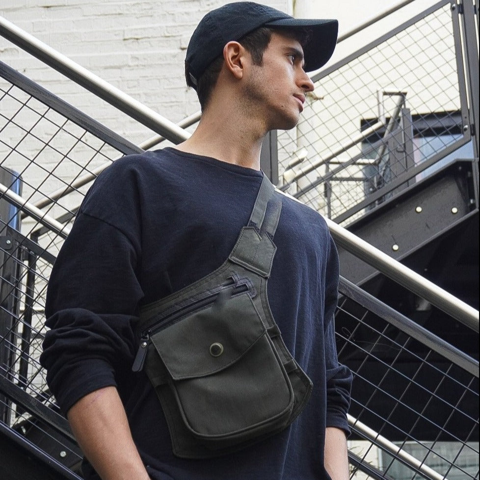 Paguro Upcycle recycled canvas crossbody bag worn by man in black cap and sweatshirt by metal stair railing