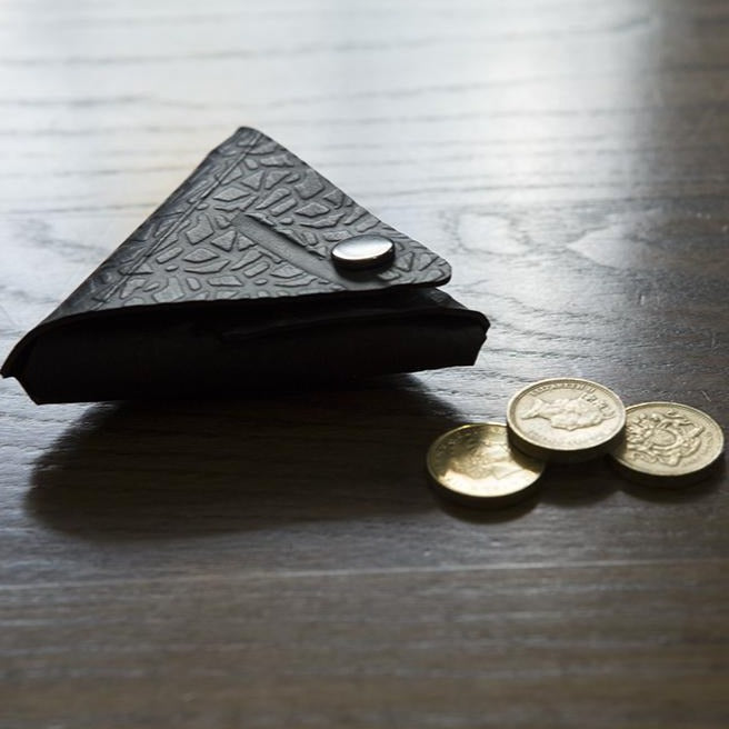 Paguro Upcycle recycled rubber coin pouch in black with textured pattern and snap button closure on wooden surface