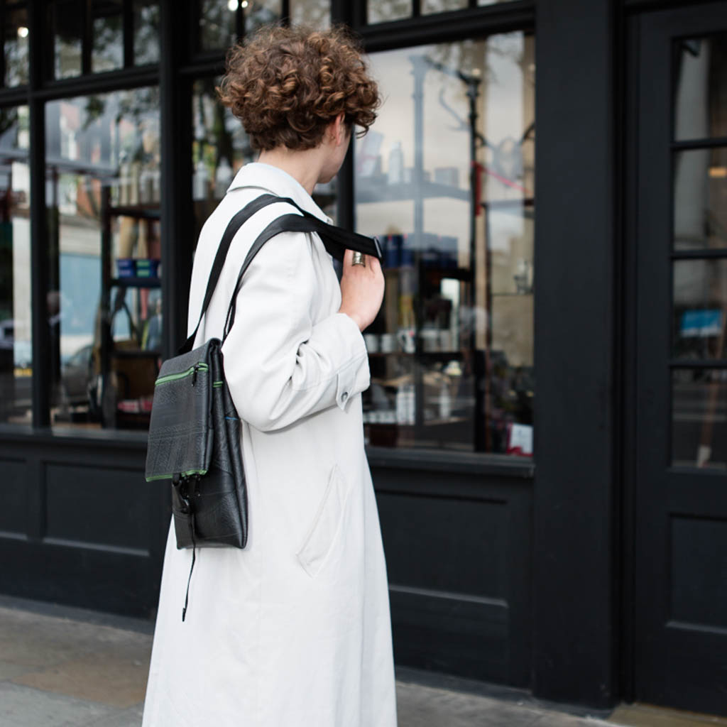 Paguro Upcycle recycled rubber crossbody bag worn by person in white coat outdoors