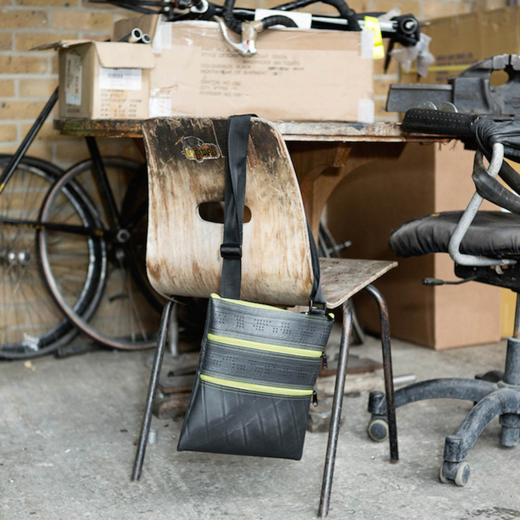 Paguro Upcycle recycled rubber vegan handbag hanging on a rustic wooden chair in a workshop