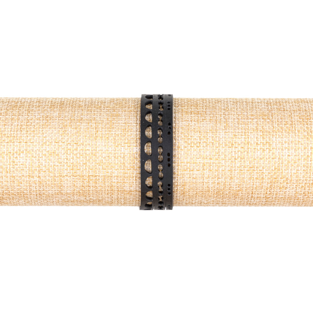 Paguro Upcycle black upcycled inner tube bracelet with cutout patterns displayed on natural fabric
