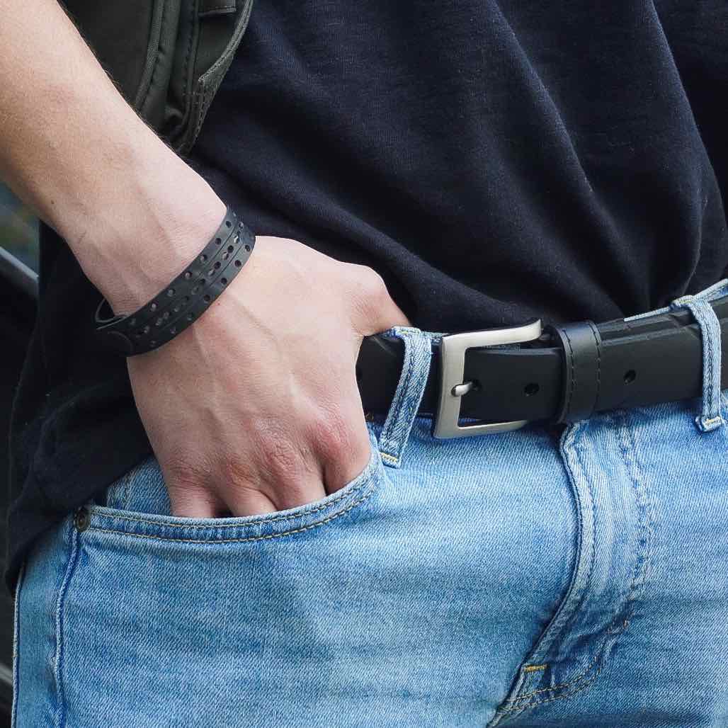 Upcycled inner tube bracelet worn on wrist with black belt and blue jeans showing casual style