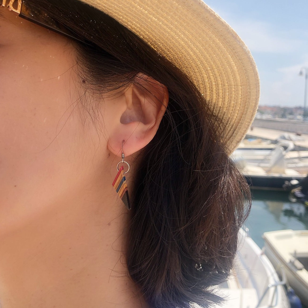 Paguro Upcycle upcycled skateboard earrings worn on ear with colorful striped design and silver hooks