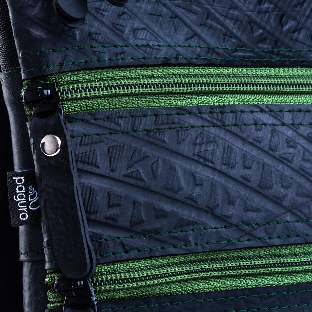 Close-up of Paguro Upcycle upcycled vegan crossbody bag showing textured black material and green zippers
