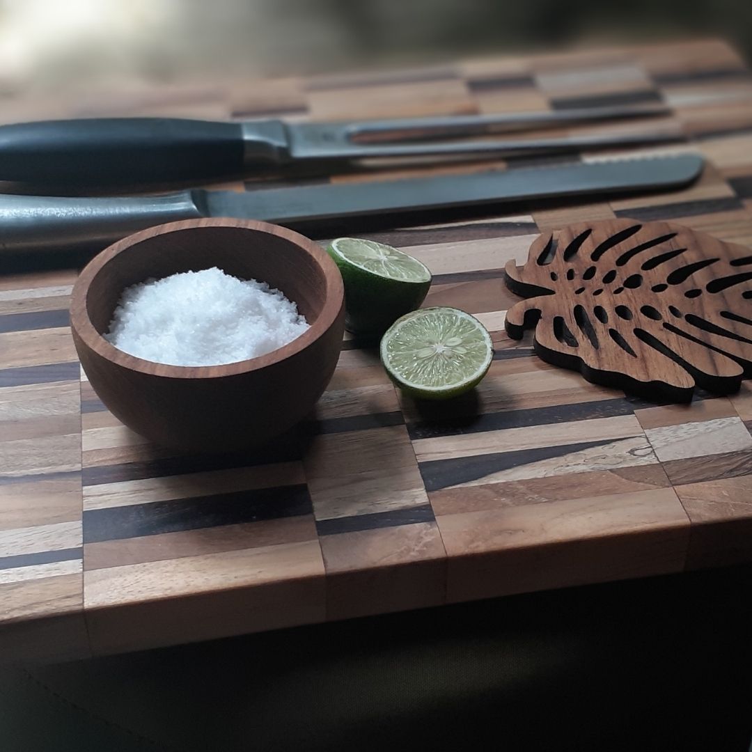 Paguro Upcycle upcycled wooden mini bowl filled with salt on a striped wooden cutting board with sliced lime and kitchen knives
