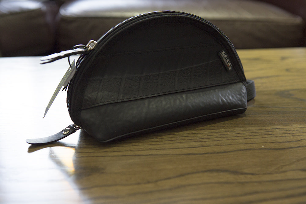 Paguro Upcycle black vegan travel pouch made from upcycled materials placed on wooden surface